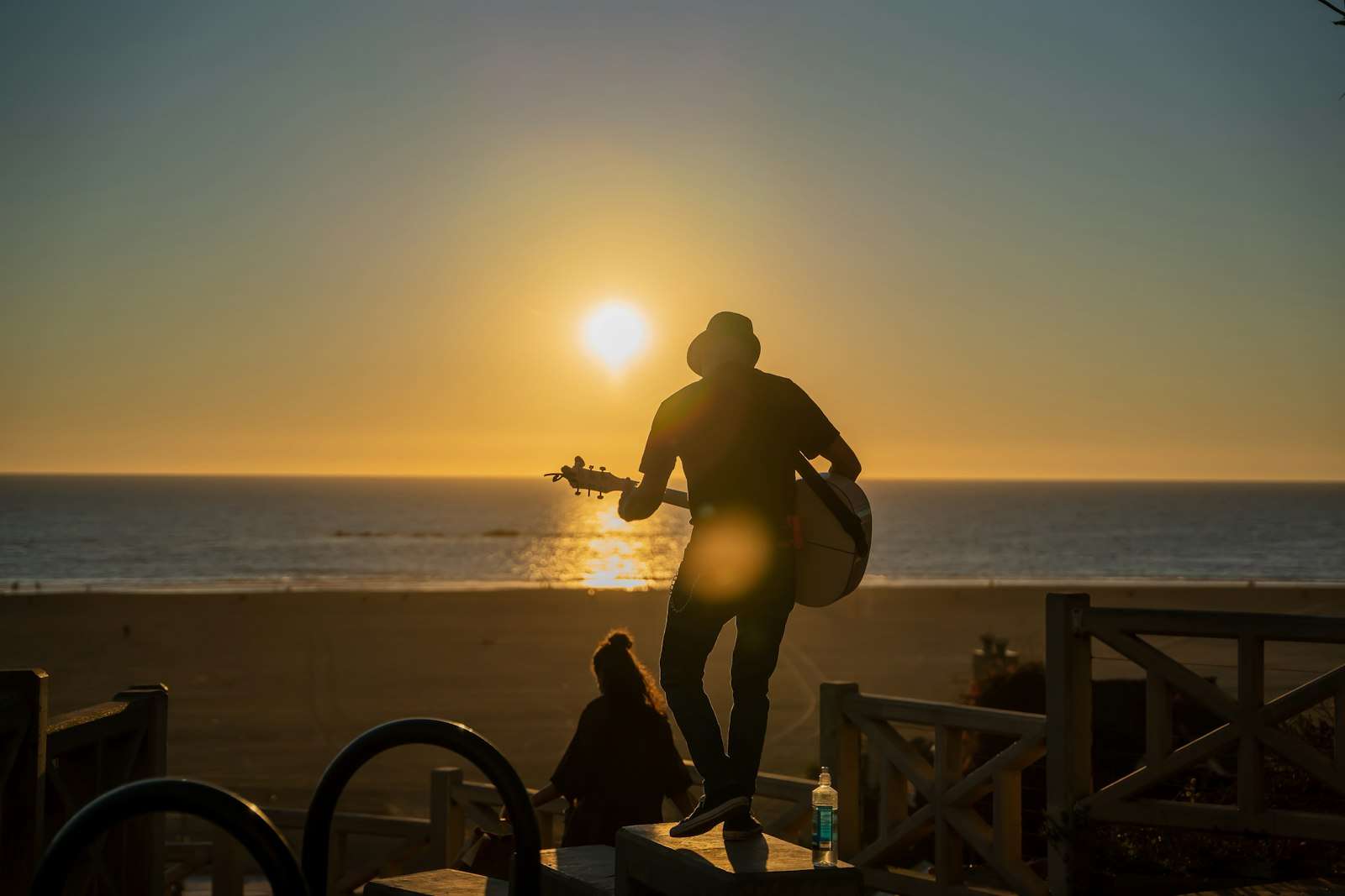 Acoustic guitarist performing on the beach at sunset near the Alabama Gulf Coast
