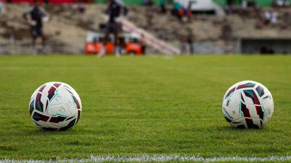Soccer balls resting on a grass pitch before a match at a stadium