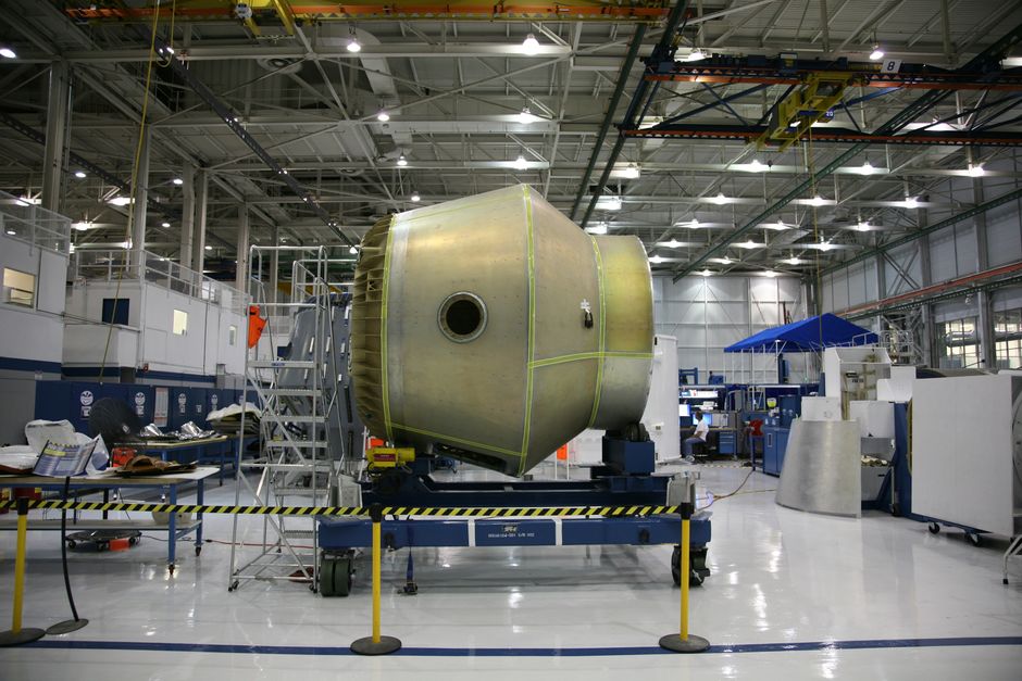 Workers on an aircraft assembly line inside a manufacturing facility