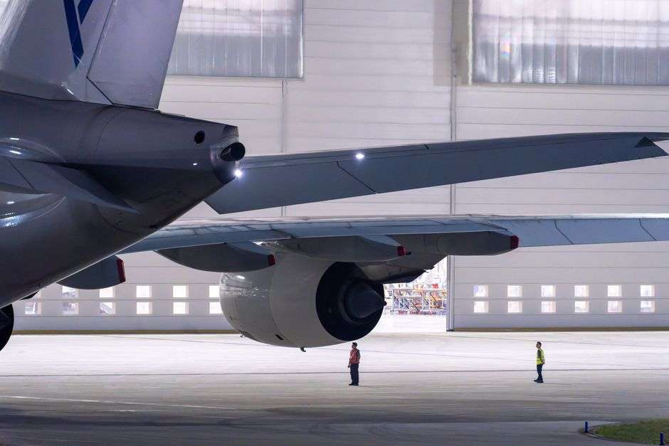 Maintenance crew members inspect a commercial aircraft inside a hangar