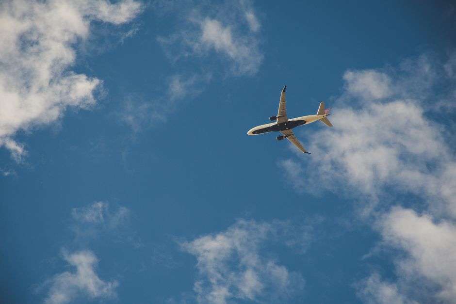 A jetliner flies over Mobile, Alabama against a clear blue sky