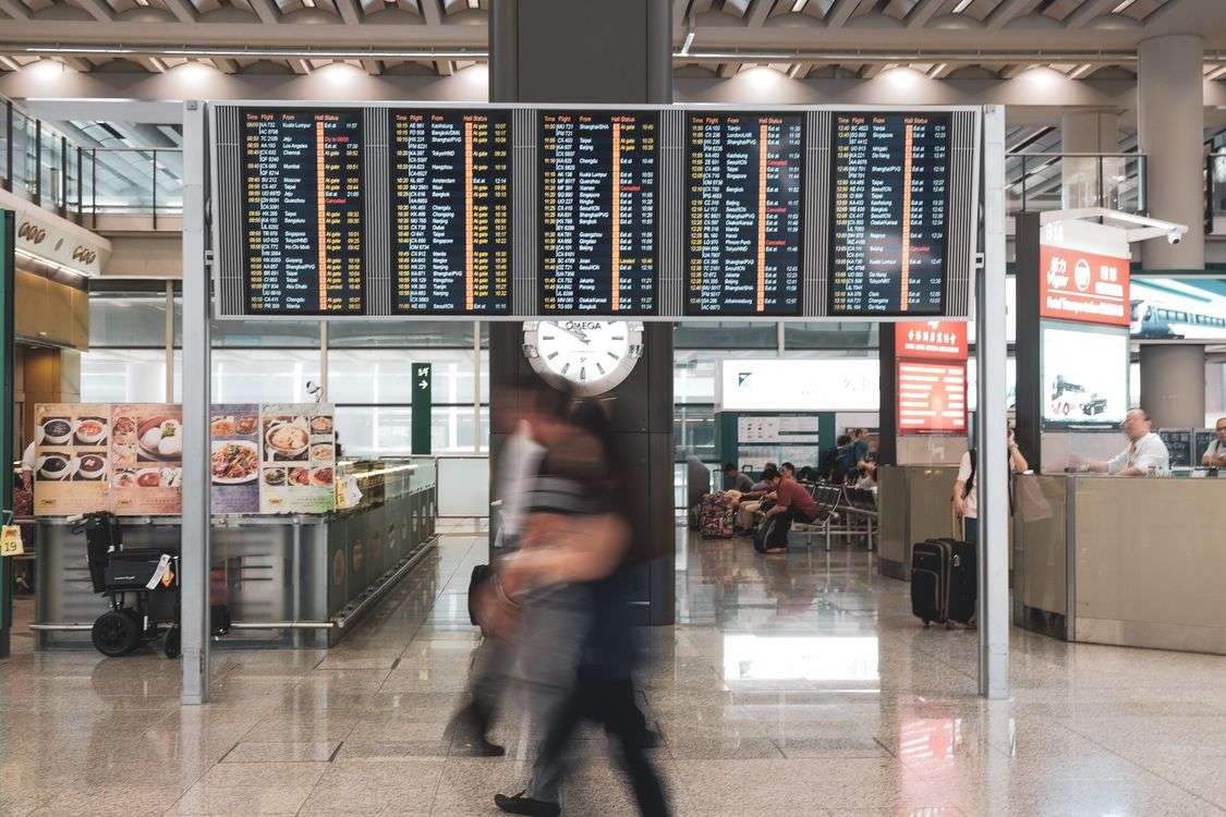 Travelers walking through an airport terminal near departure information screens