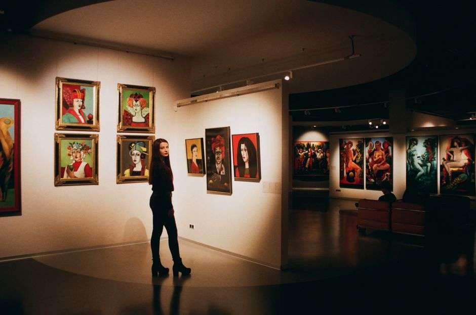 A visitor views paintings displayed on the wall of a contemporary art gallery