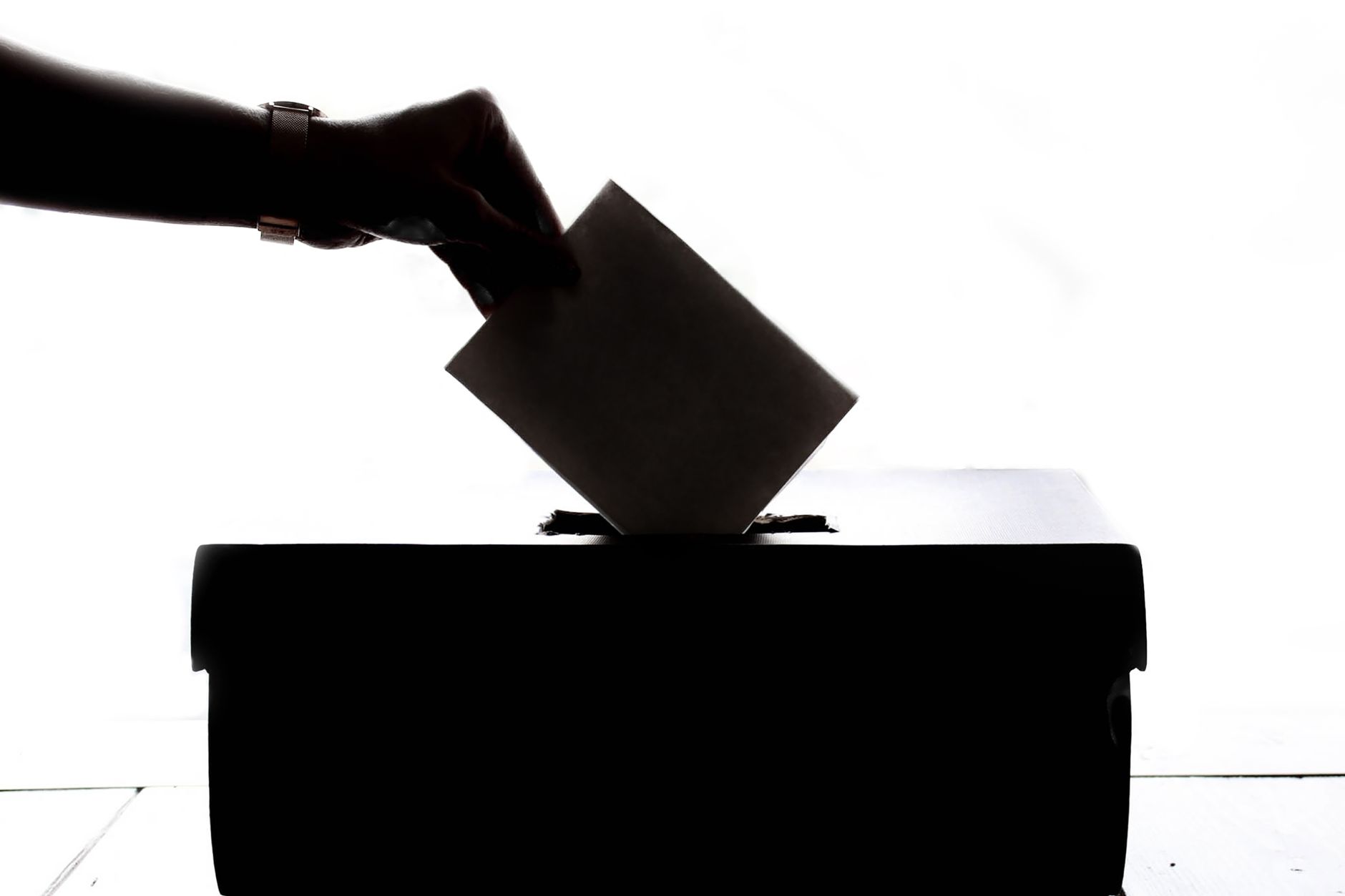 Hand placing a paper ballot into a ballot box