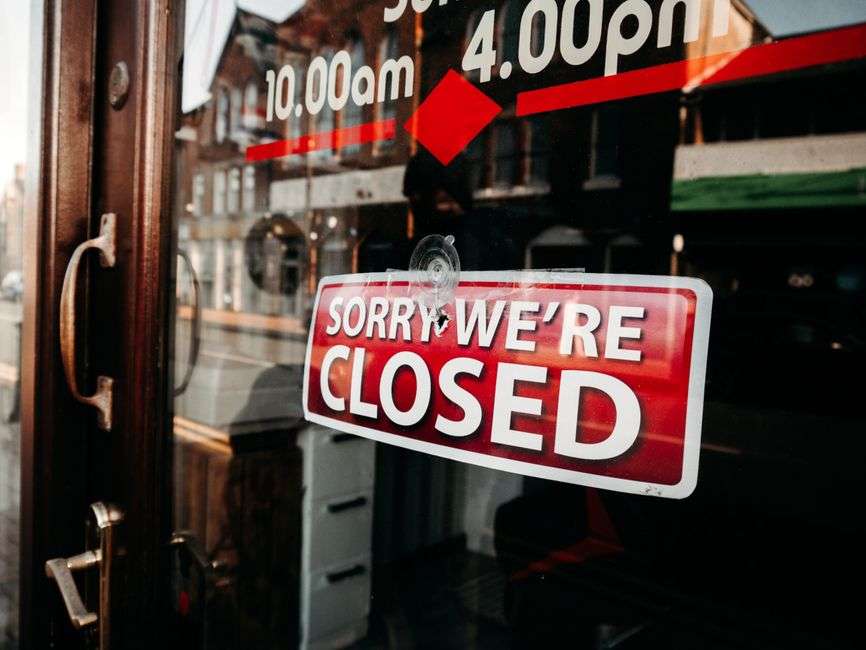 A closed sign hangs on the glass door of a small storefront