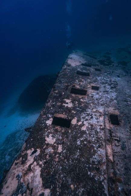 A scuba diver exploring a large artificial reef structure underwater