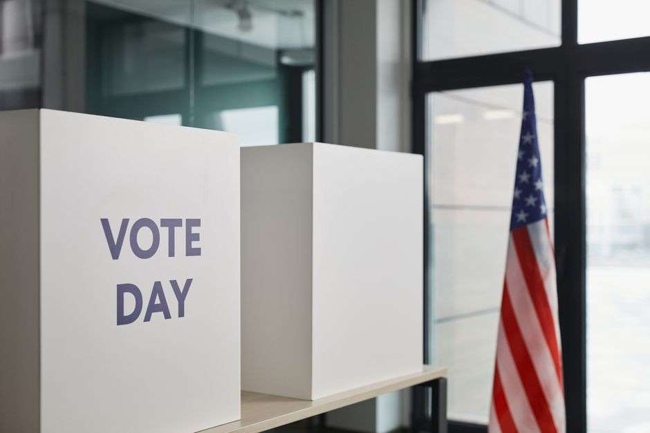 Voting booths set up for an election, with an American flag in the background