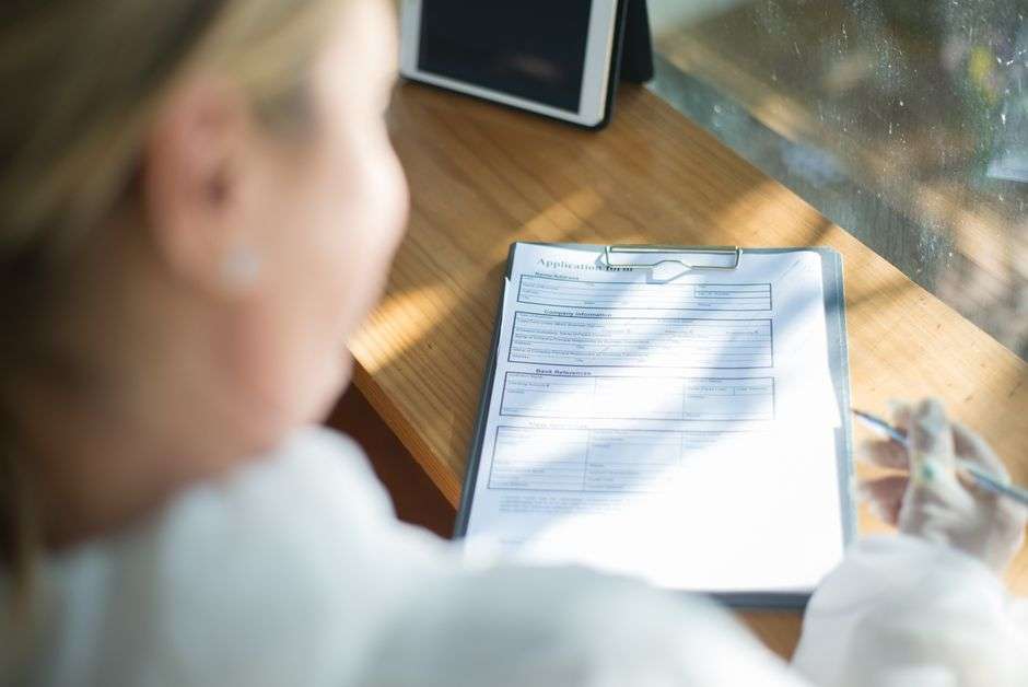 A woman fills out a job application form at a desk amid rising unemployment