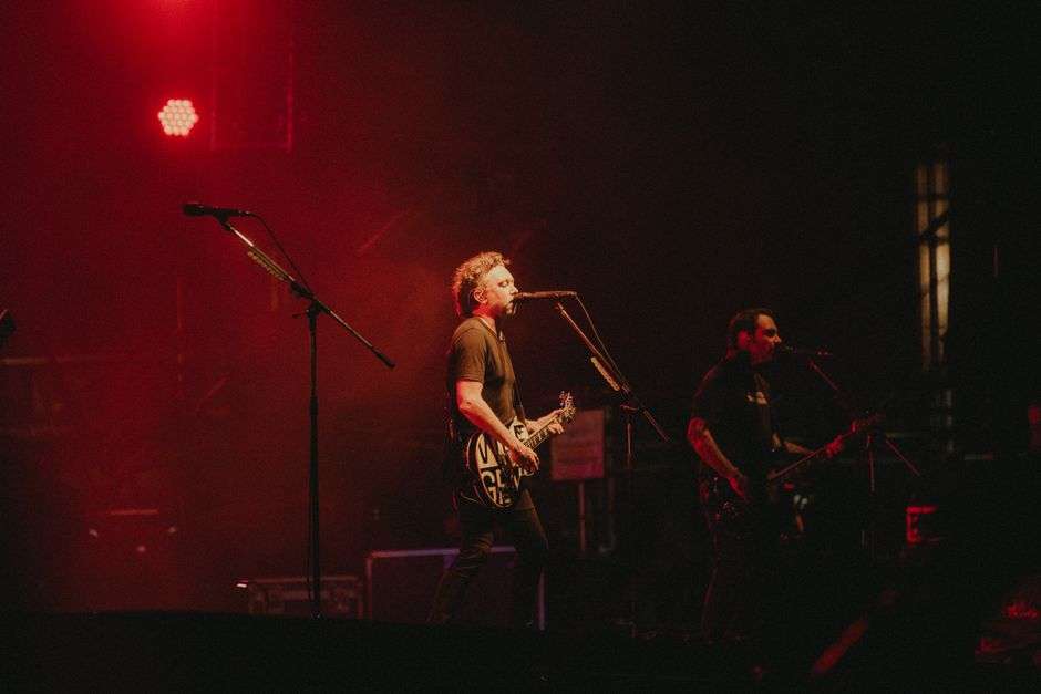 A band performs live under stage lighting at a local music venue
