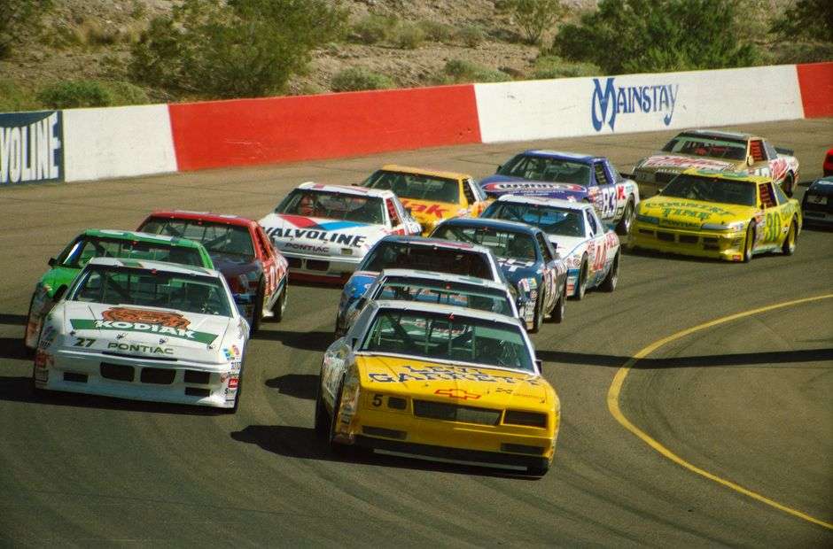 Stock cars racing side by side on a paved oval track