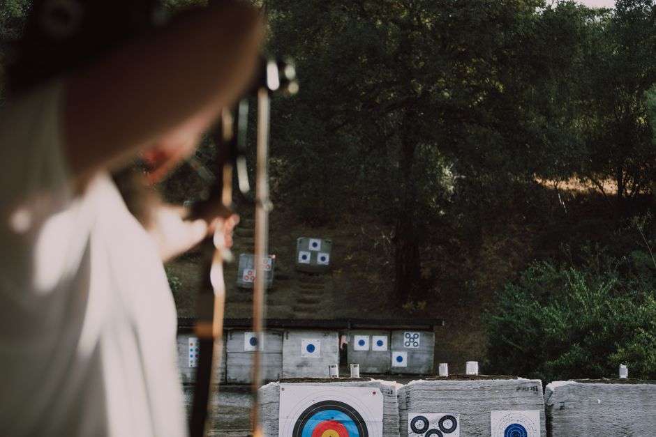 An archer takes aim at a 3D target outdoors during a competitive archery event