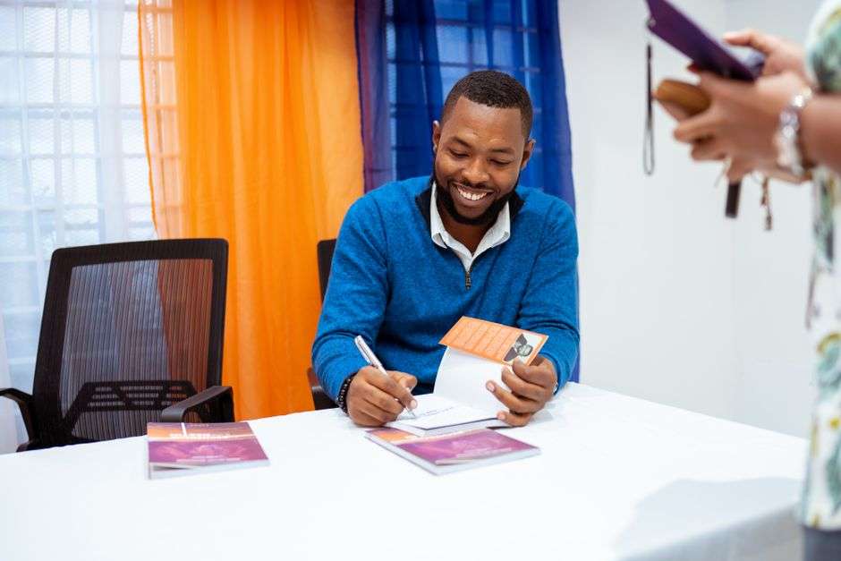 An author signs copies of his book for readers at a public event