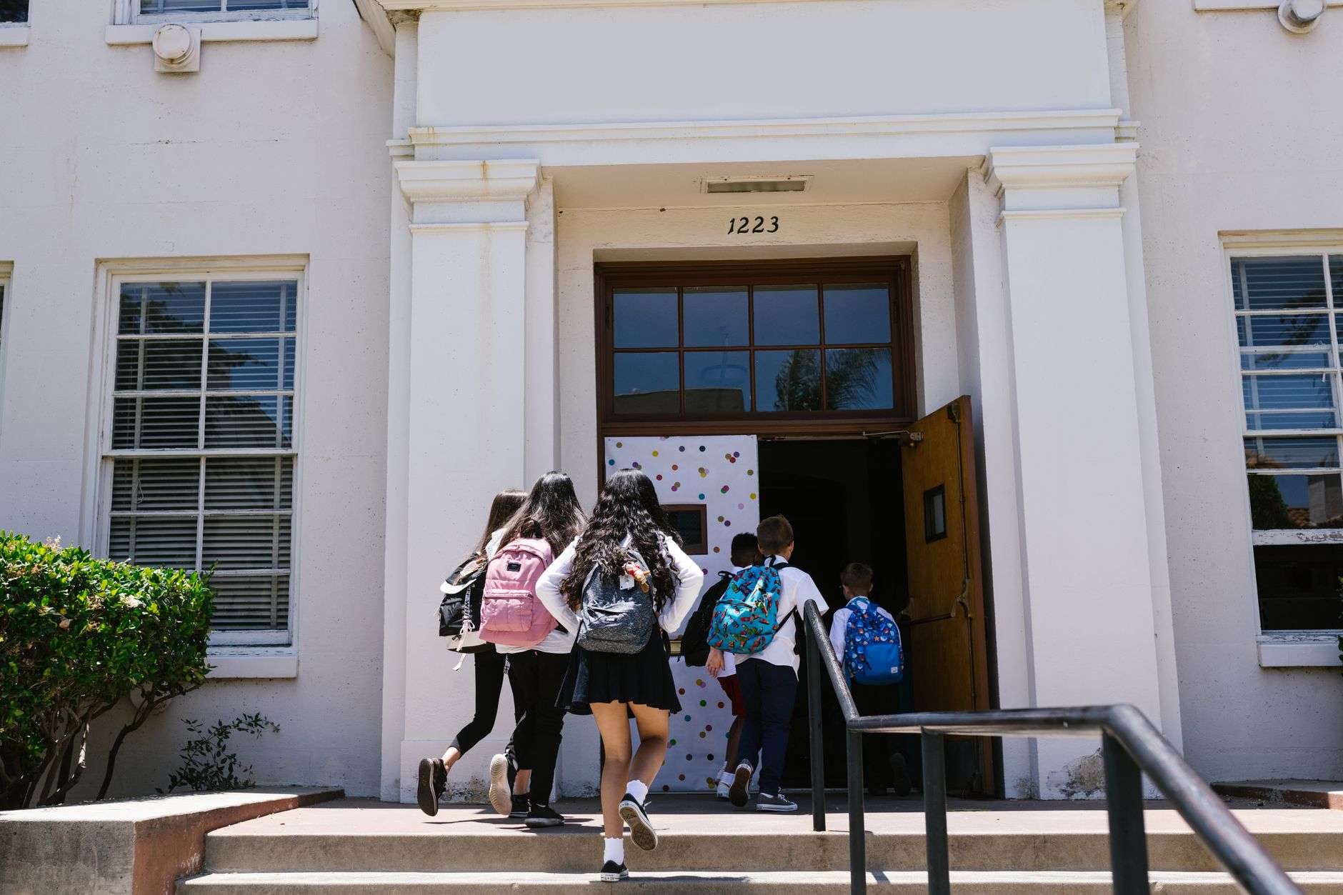 Group of elementary students with backpacks entering a school building