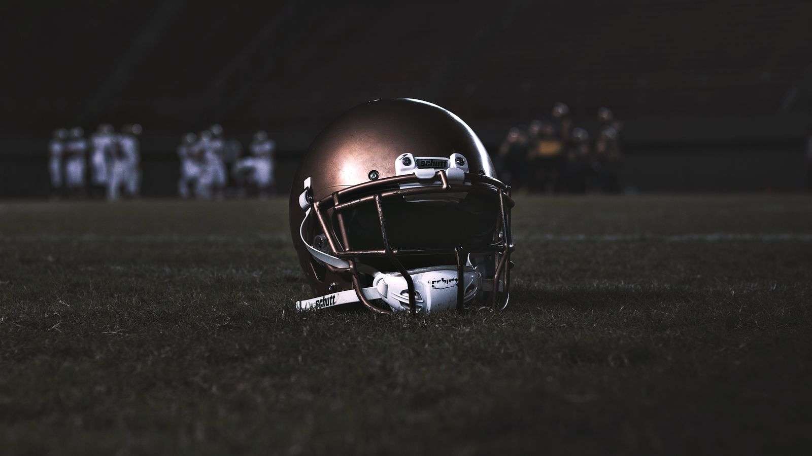 Football helmet resting on the grass under stadium lights before a night game