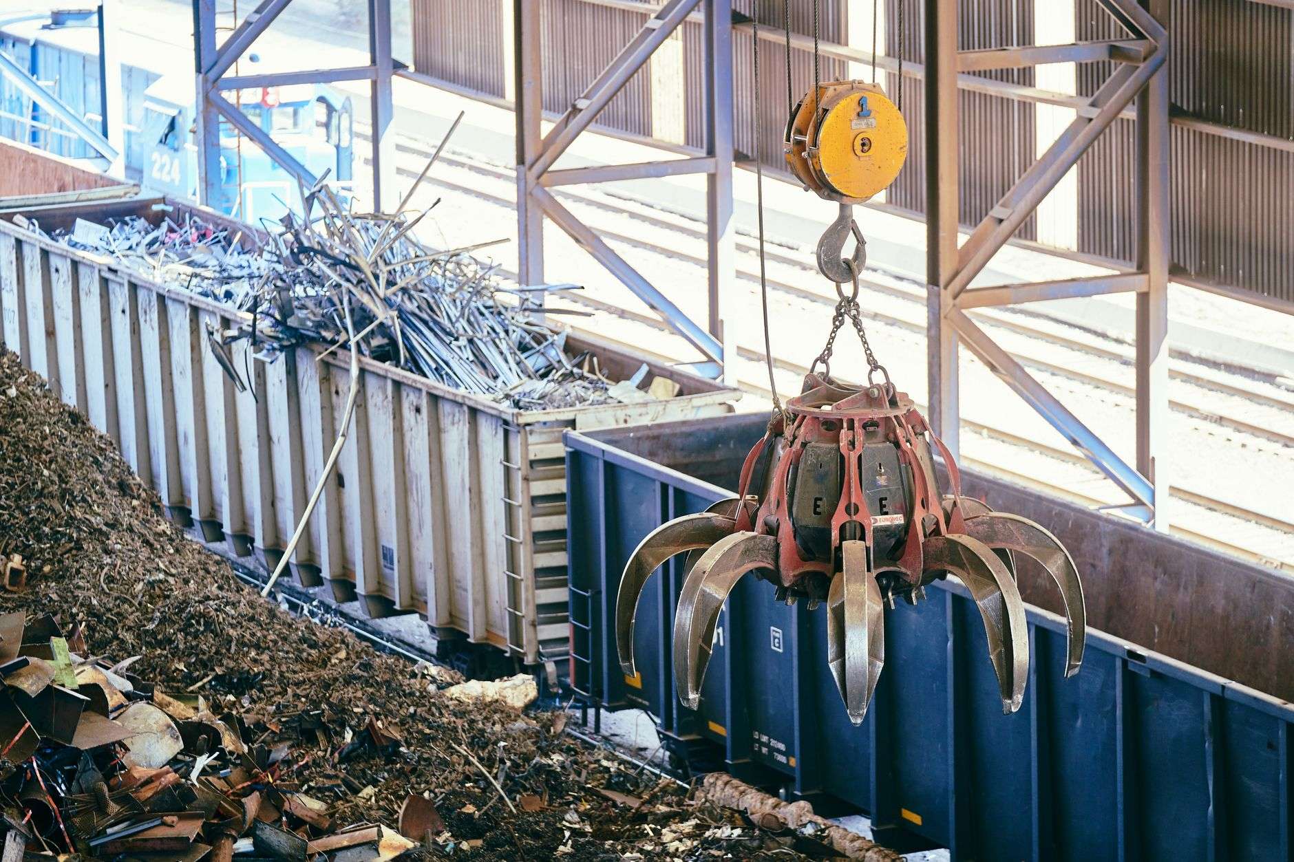 An overhead crane sorting scrap metal at an industrial recycling facility