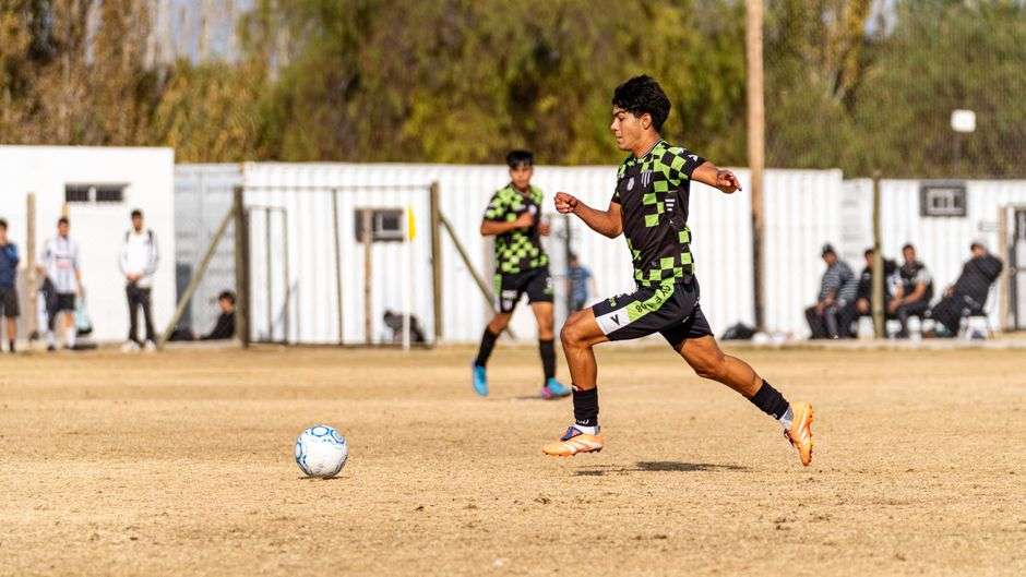 High school soccer player sprinting on a grass field during a match