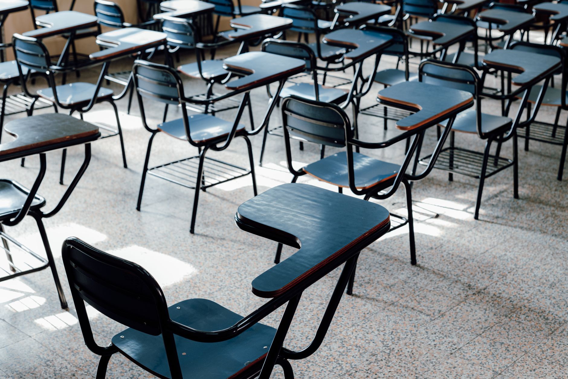 An empty classroom with desks representing a public school system