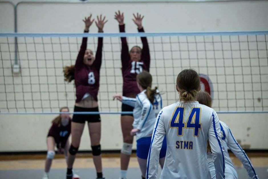 High school volleyball players compete at the net during a state championship match