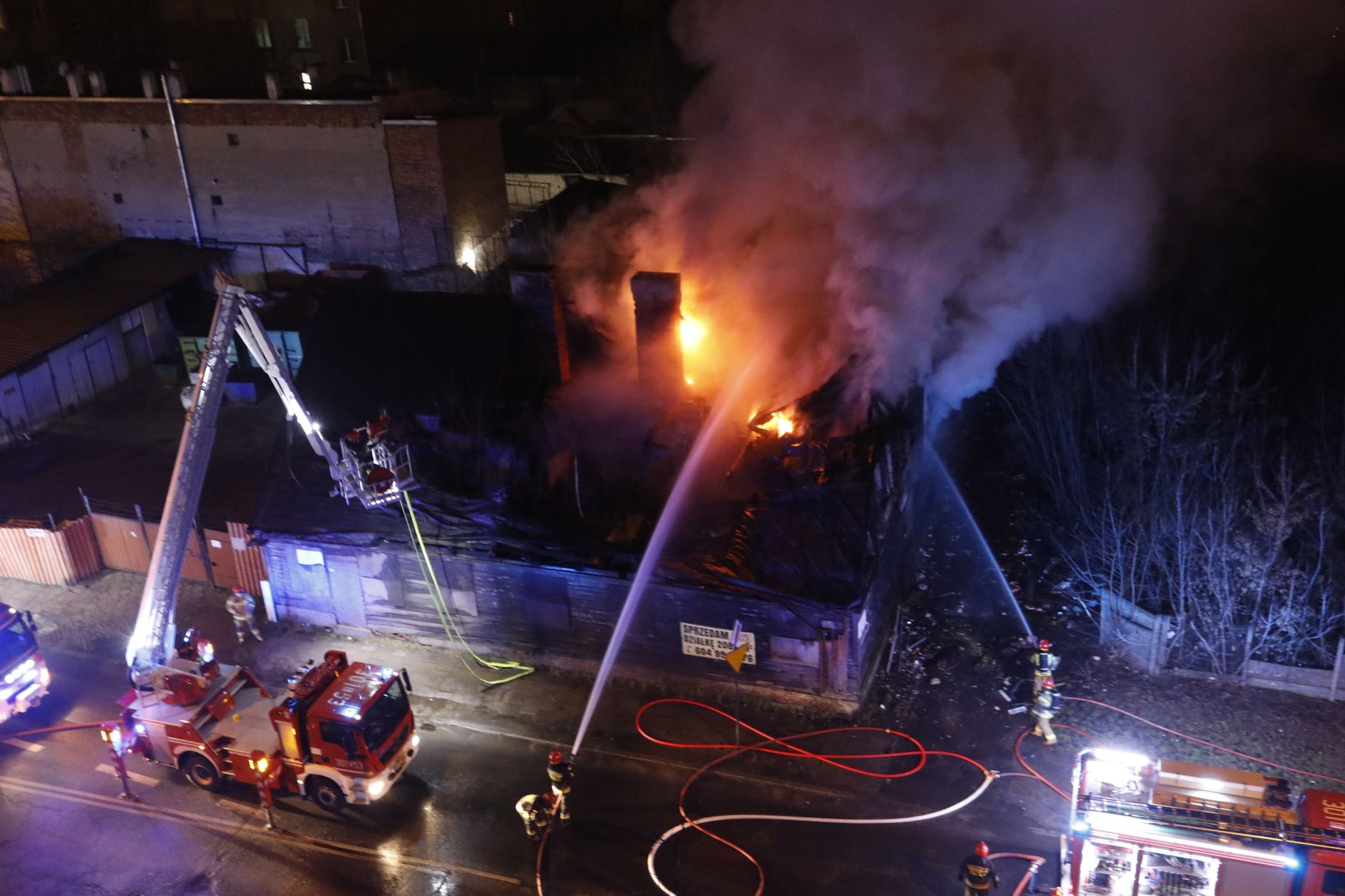 Firefighters directing hose streams at a burning residential structure at night