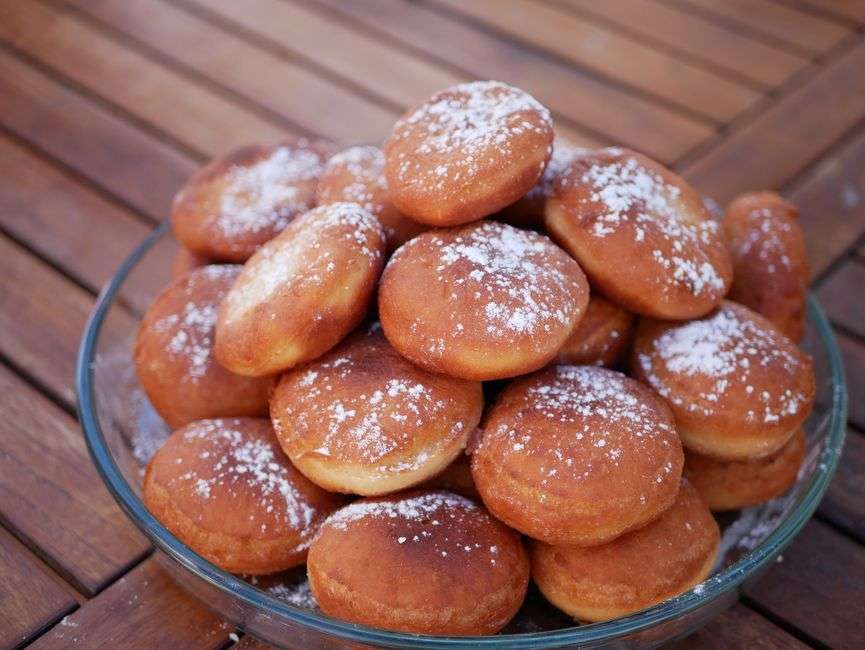 Freshly baked beignets dusted with powdered sugar on a plate