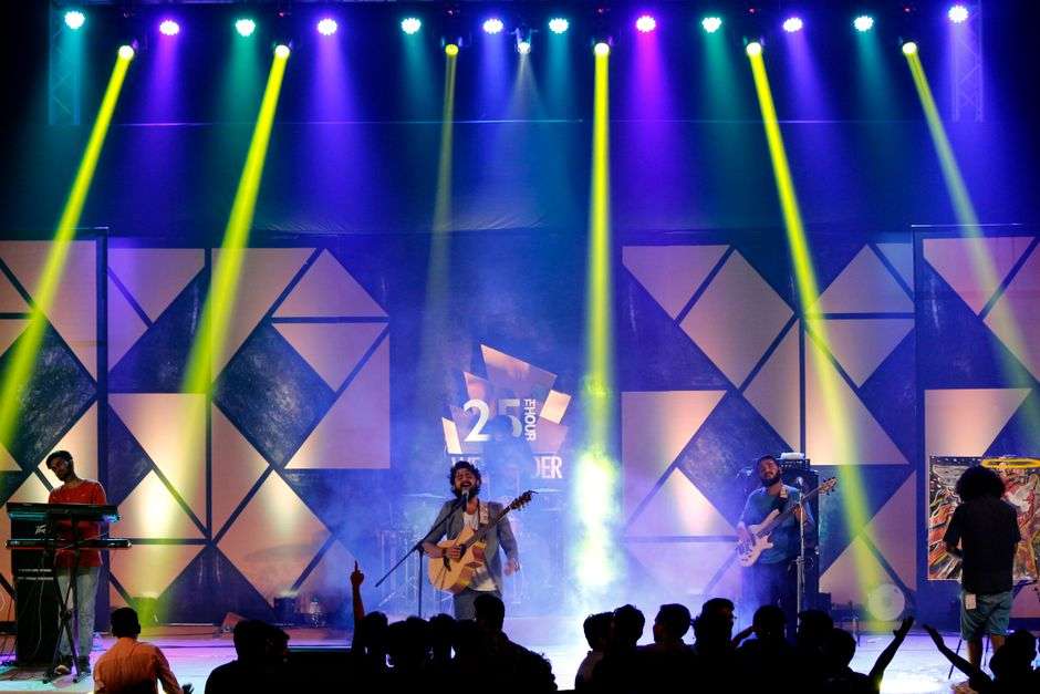 Musician playing guitar and singing on stage under bright concert lighting