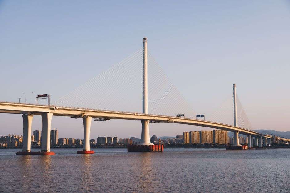 Cable-stayed bridge spanning a wide river at sunset