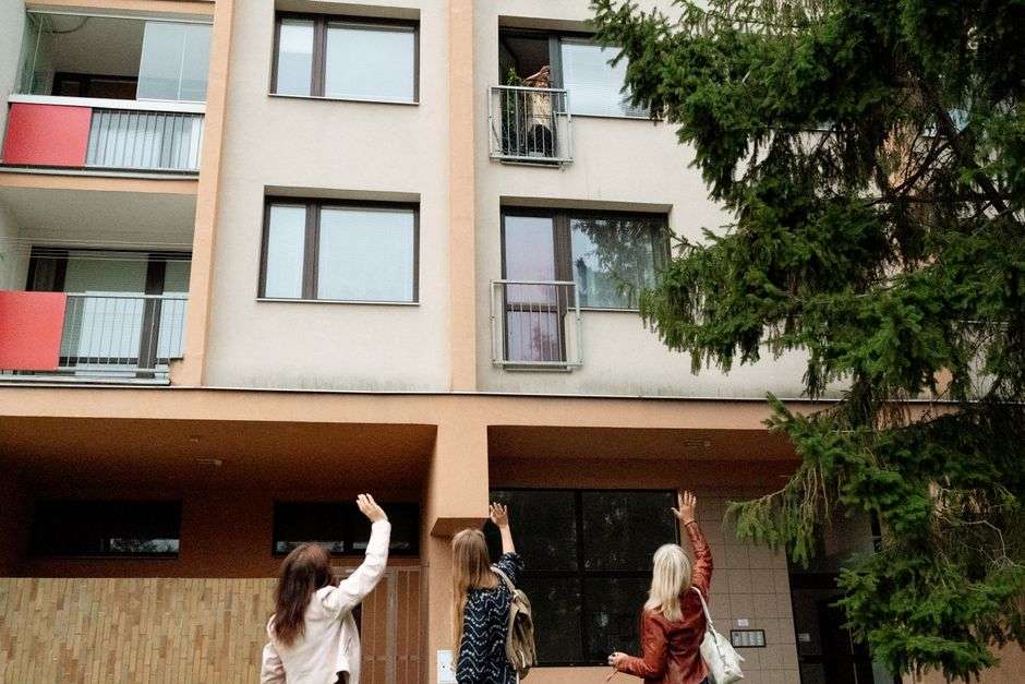 Residents wave from balconies at a senior apartment building