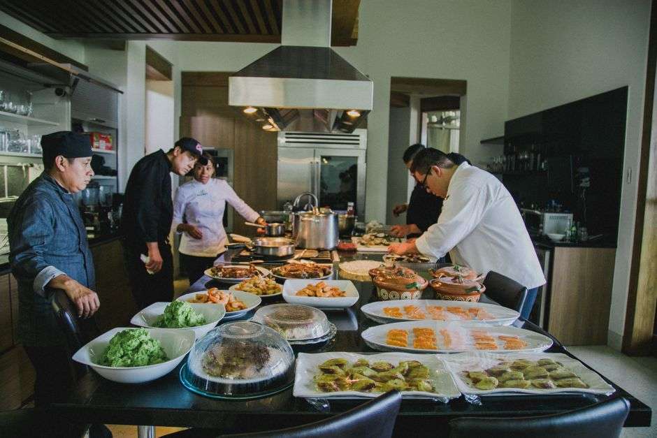 Chefs prepare a spread of dishes on a table for a charity food tasting event