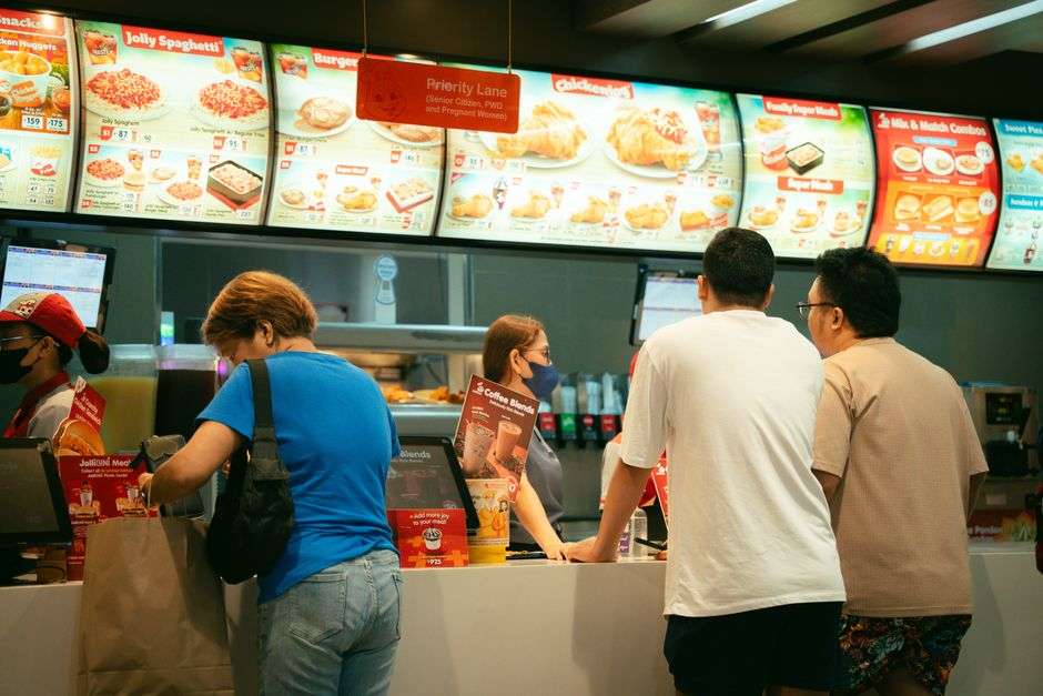 Customers order food at a busy fast food restaurant counter