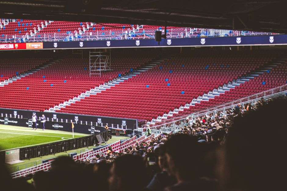 Fans sit in stadium bleachers during a high school football game