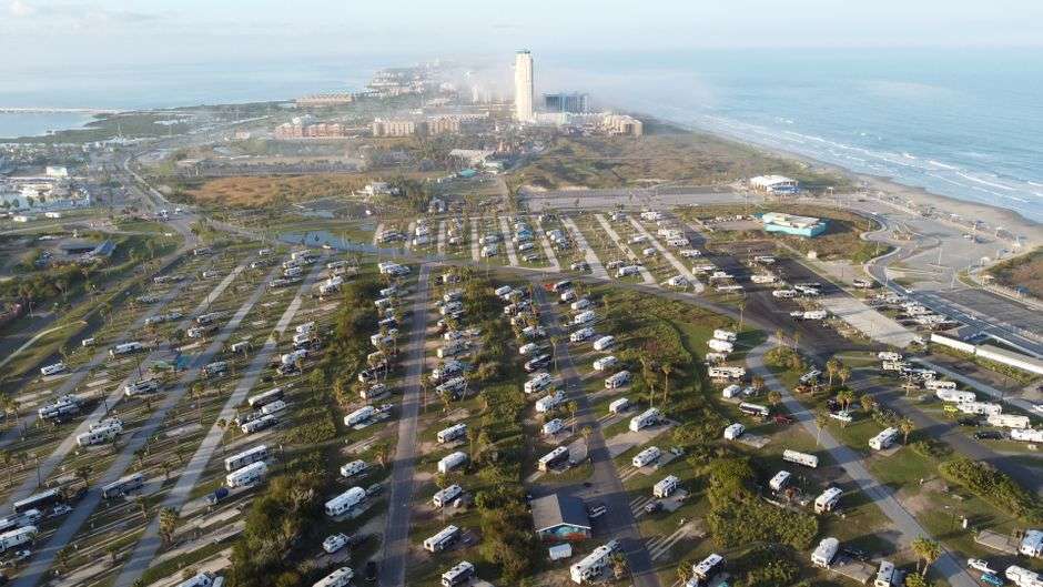 Aerial view of RVs parked in rows at a coastal resort near the beach