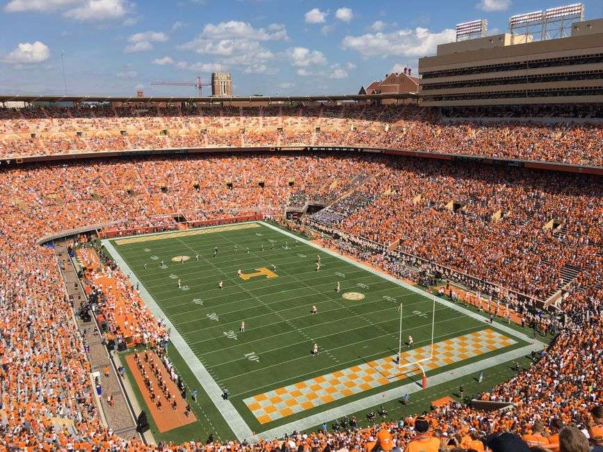 A packed college football stadium during a game, viewed from an aerial angle