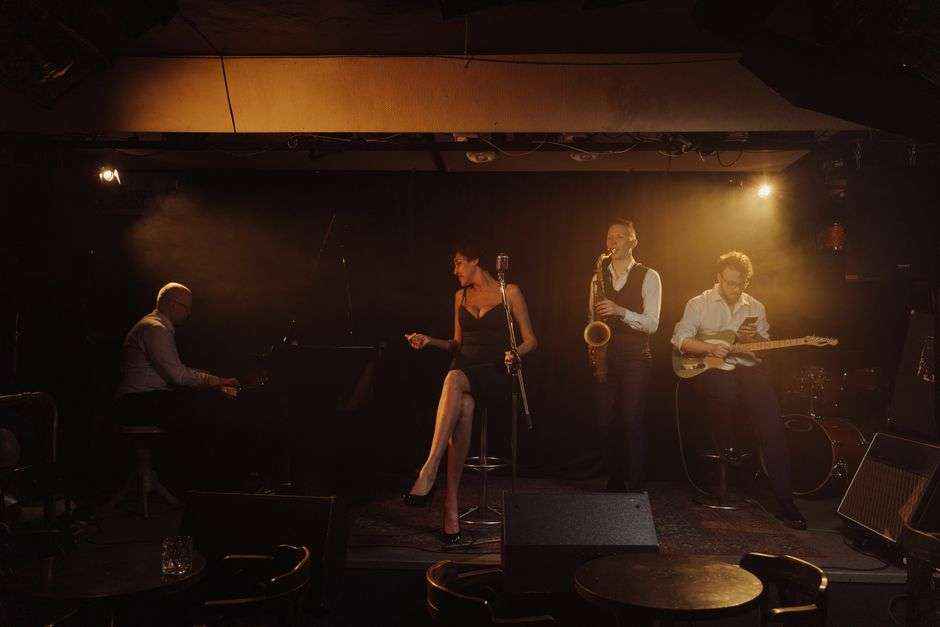 A jazz band performs on stage with saxophone, keyboard and guitar during a live club show