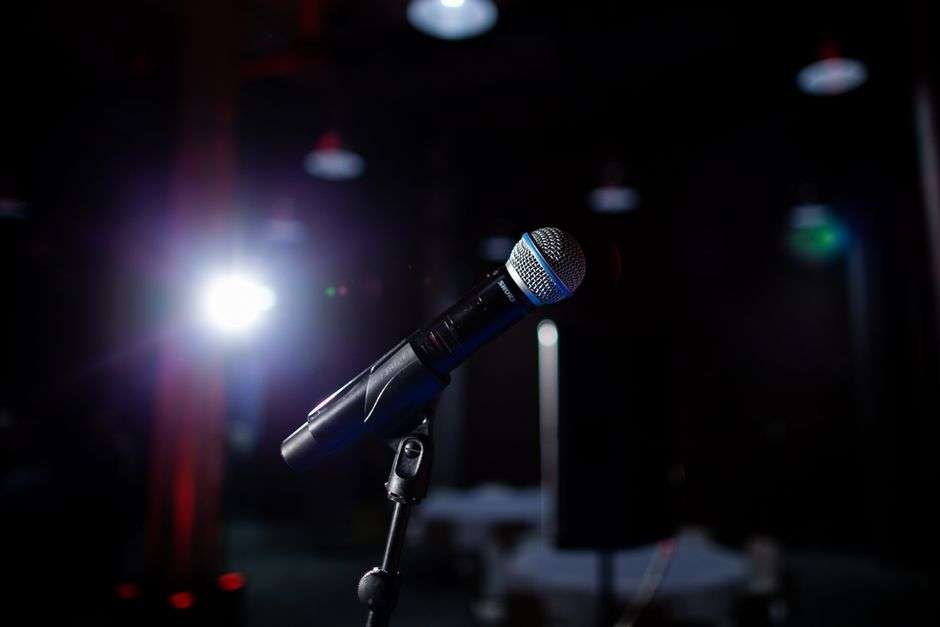 A microphone stands under a spotlight on an empty stage ahead of a comedy performance