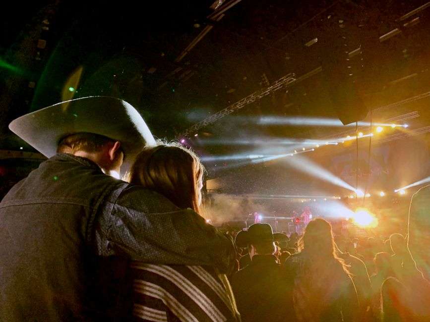 Performers sing under colorful stage lights during a live country music concert