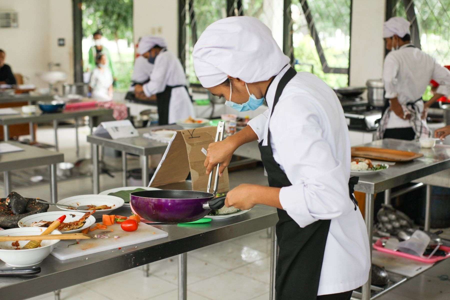High school culinary students preparing dishes in a professional kitchen