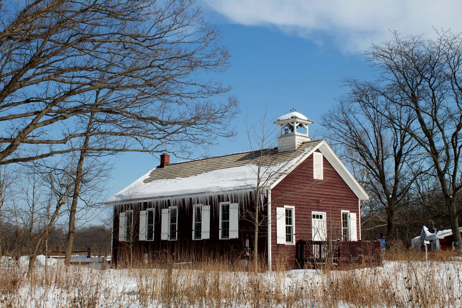 A small historic red one-room schoolhouse on a coastal island