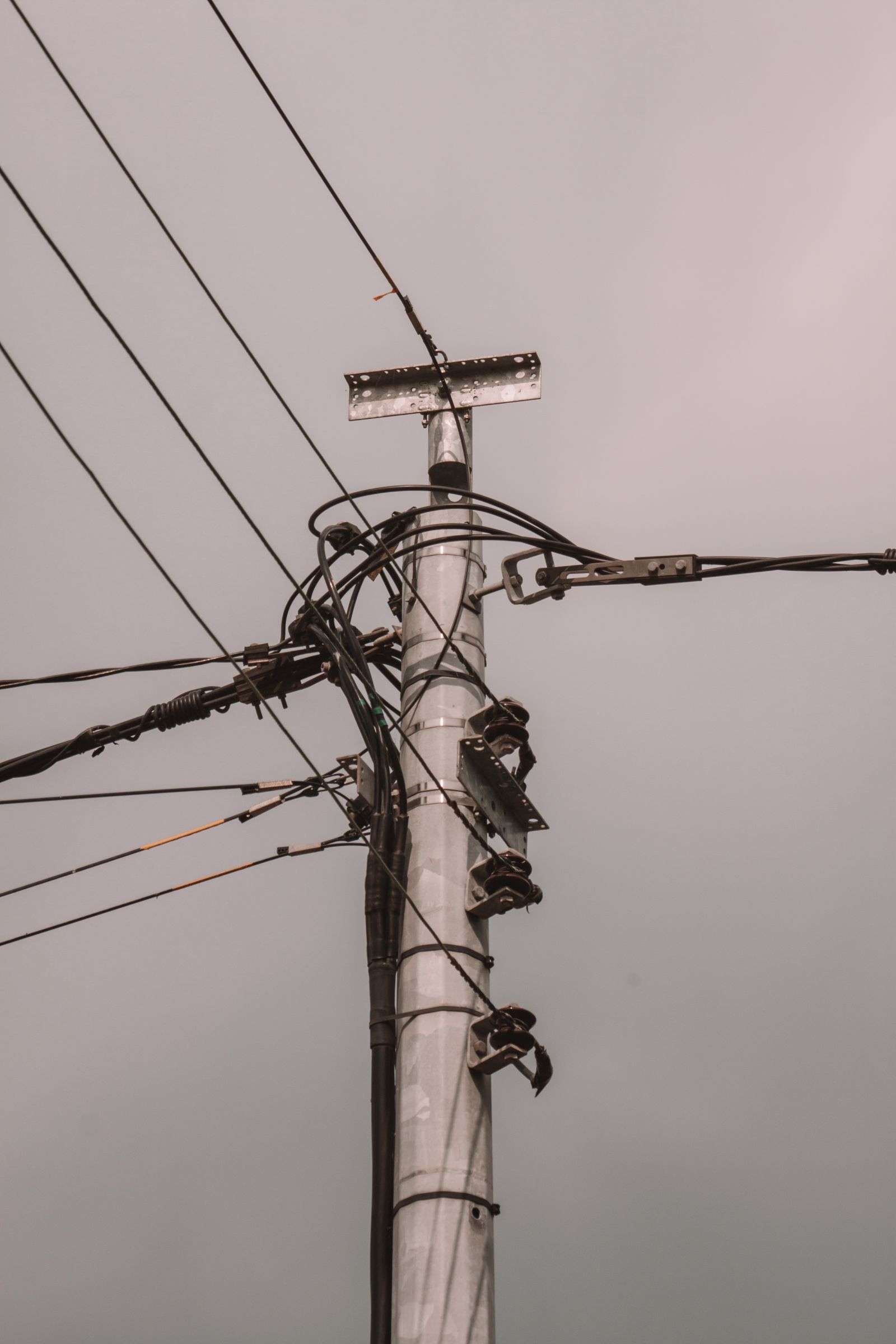 Utility pole and overhead power lines against an overcast sky, representing electrical repair work