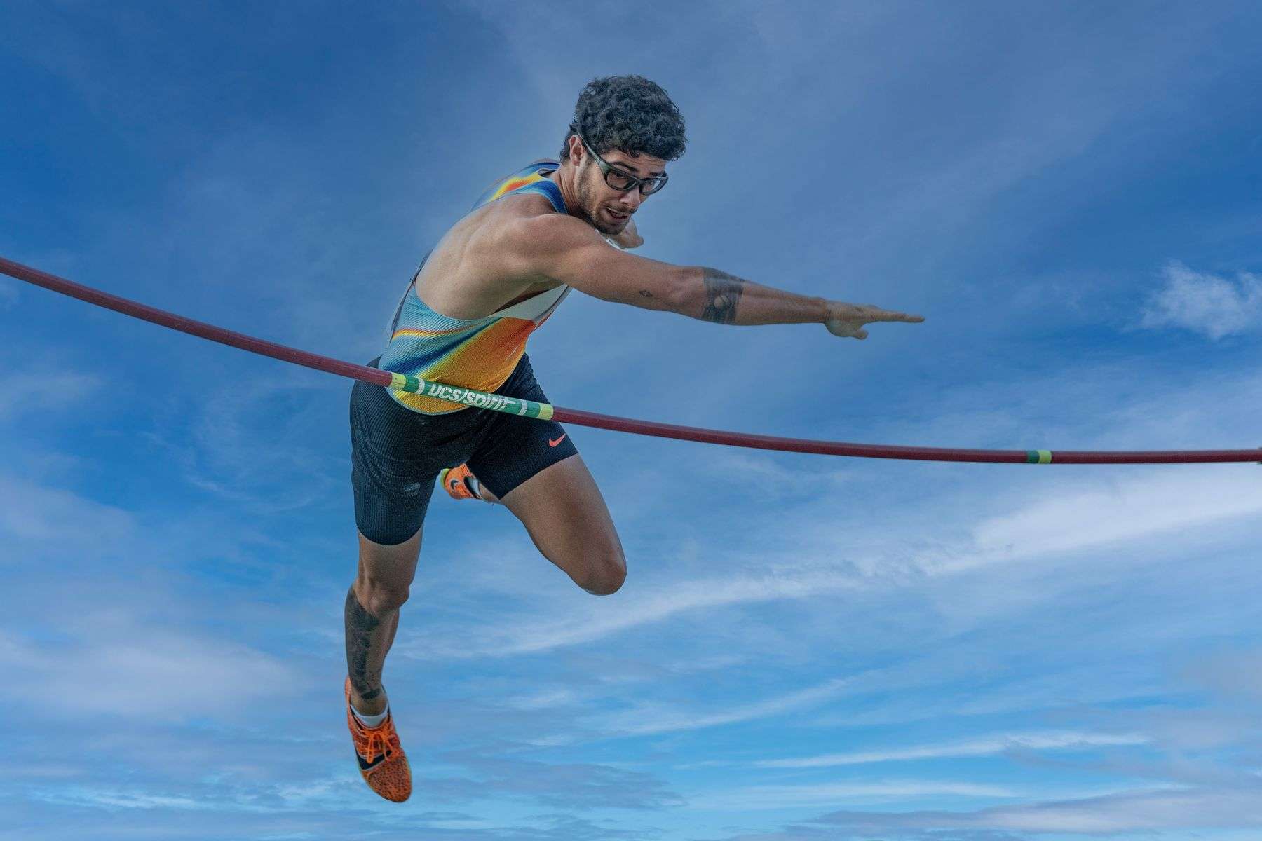 A pole vaulter clearing the bar during an outdoor competition