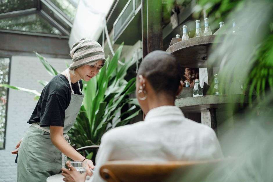 Smiling waitress in uniform serving food to a customer in a cozy restaurant