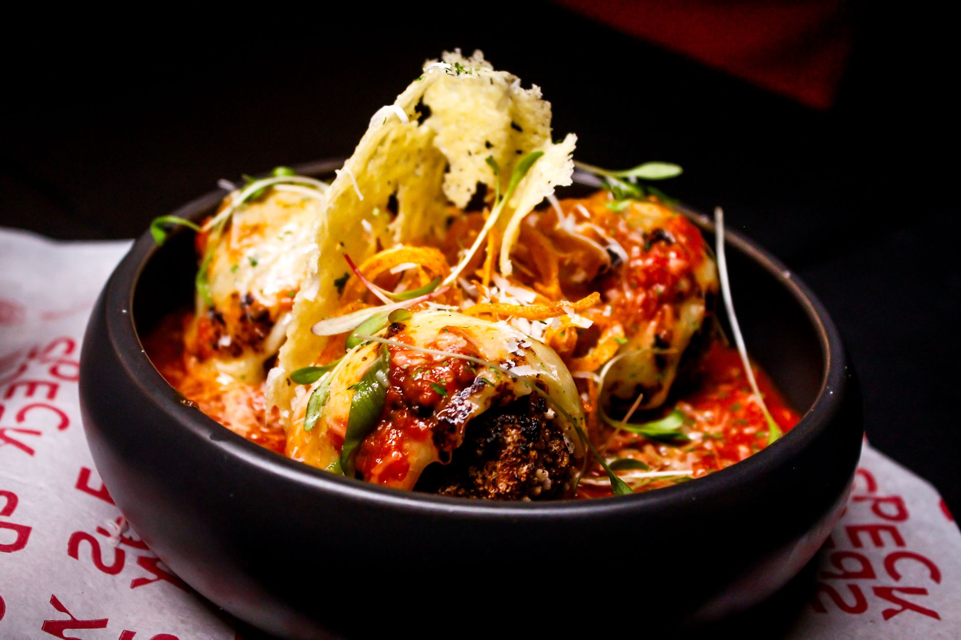 A bowl of meatballs in tomato sauce garnished with herbs