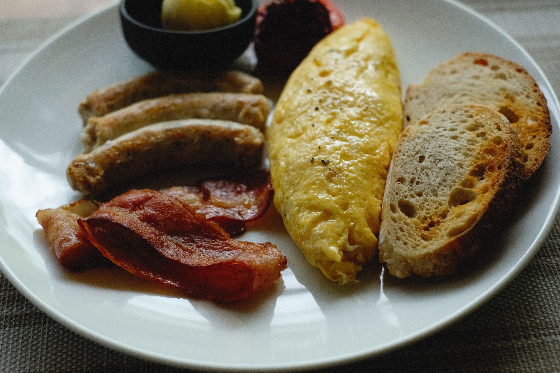 A folded omelet with sausage and cream cheese beside crispy bacon