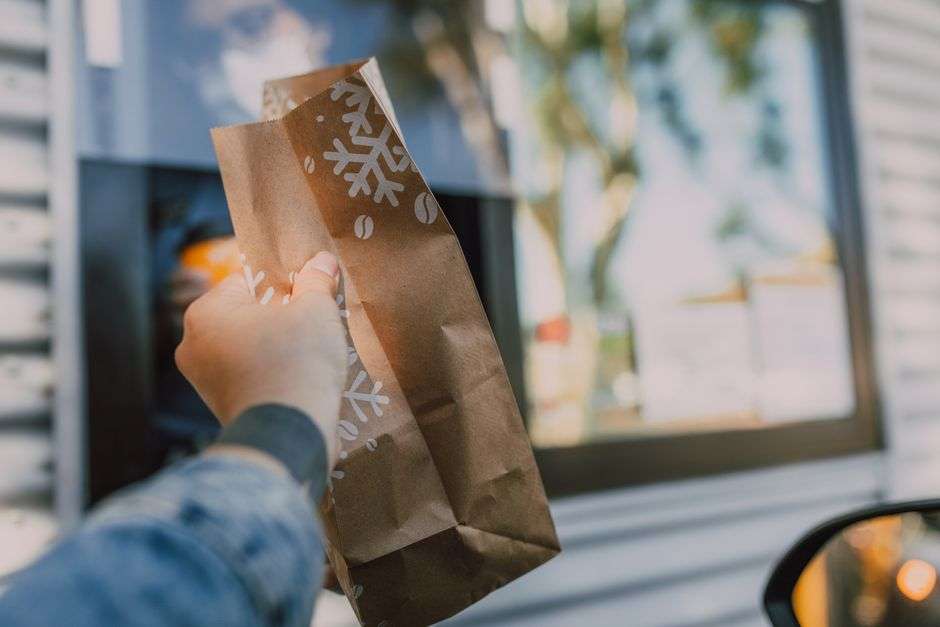 A customer picks up a to-go food order at a restaurant drive-thru window