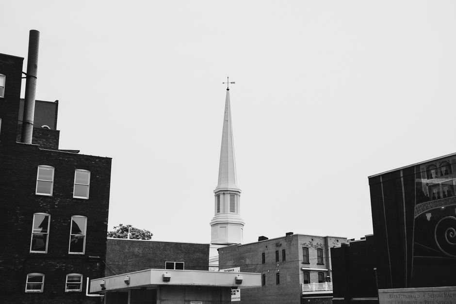 Red brick historic church building with a tall steeple in a downtown setting