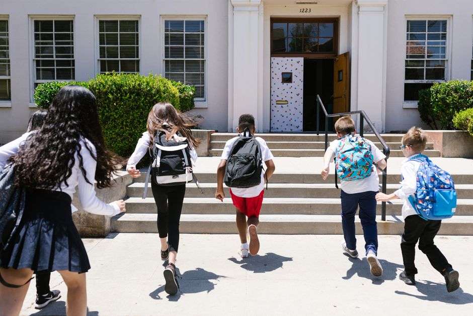 Students with backpacks arriving at an elementary school