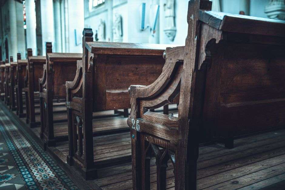 Rows of empty wooden pews inside a Catholic church