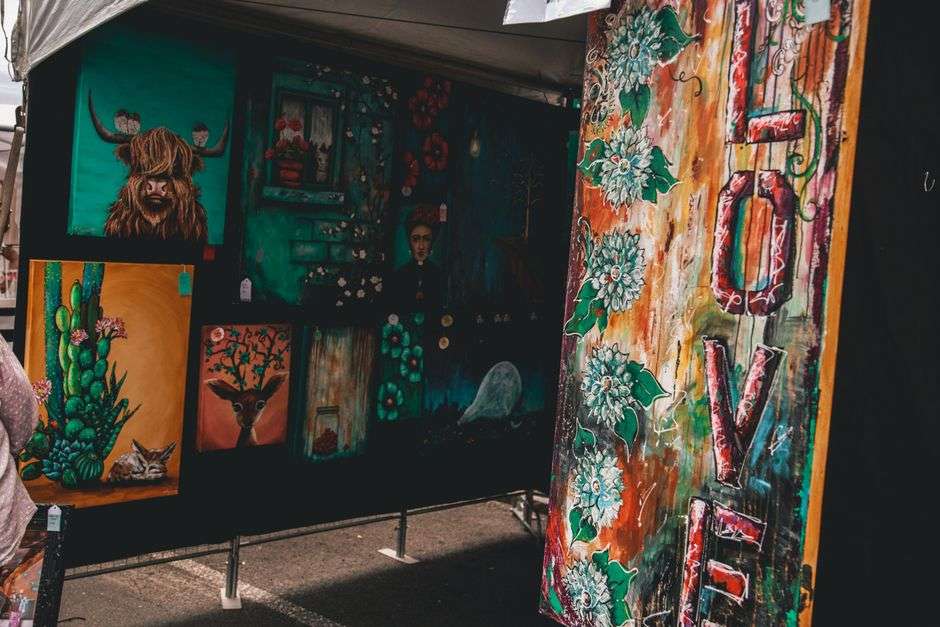 Colorful handmade artwork and paintings on display at an outdoor arts and crafts festival