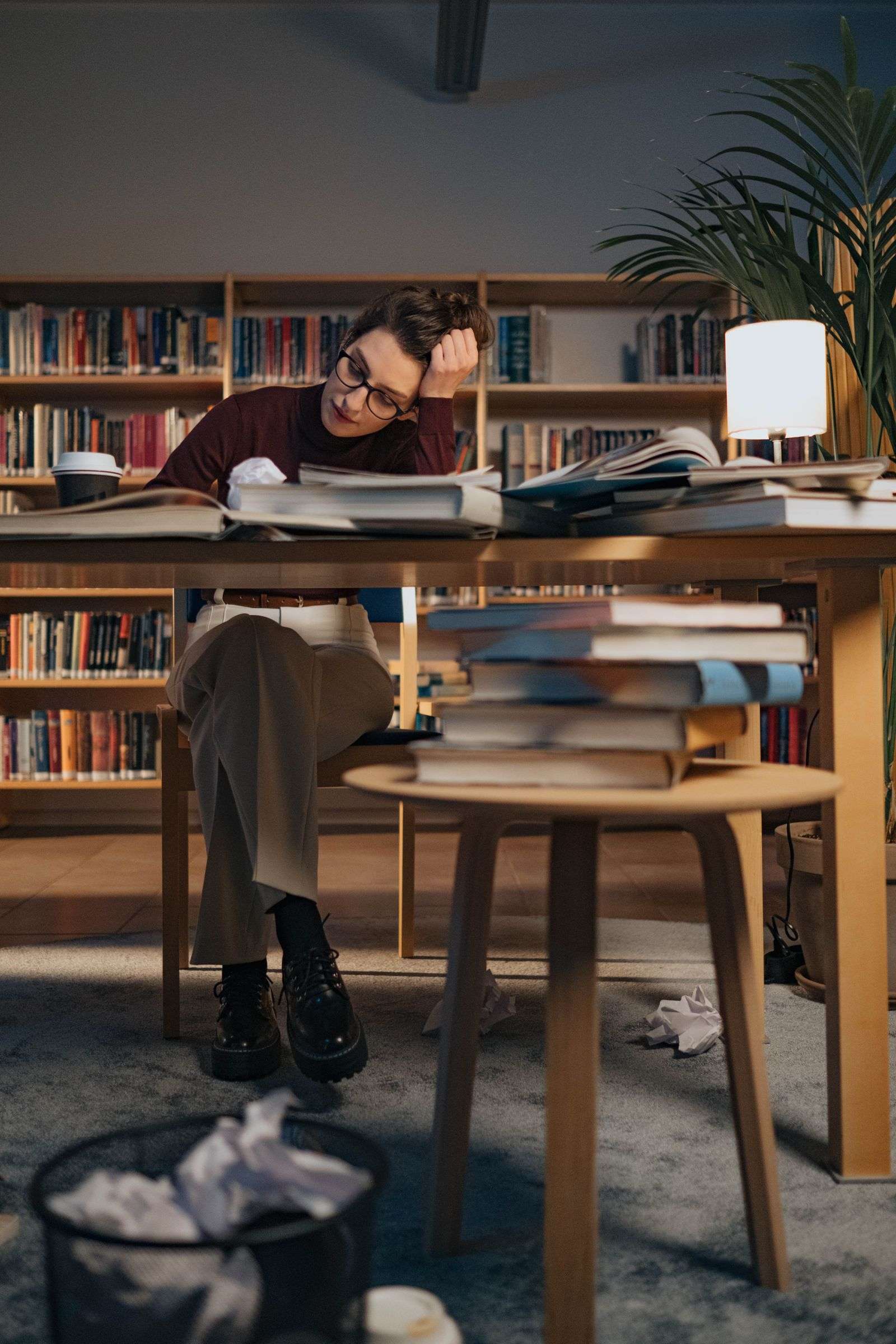 A woman author writes at a desk surrounded by books, evoking Fairhope novelist Judith Richards at work
