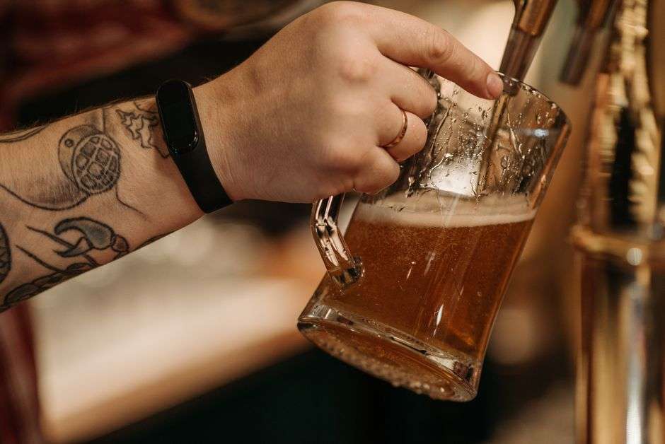 A glass of dark craft beer being poured from a tap at a brewery