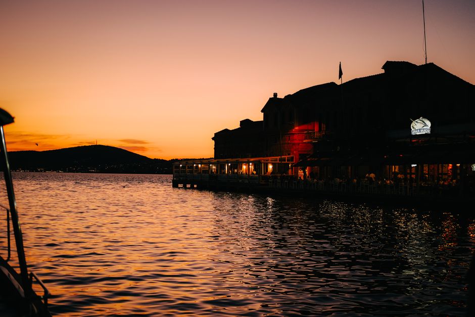 A waterfront restaurant deck at a marina during sunset